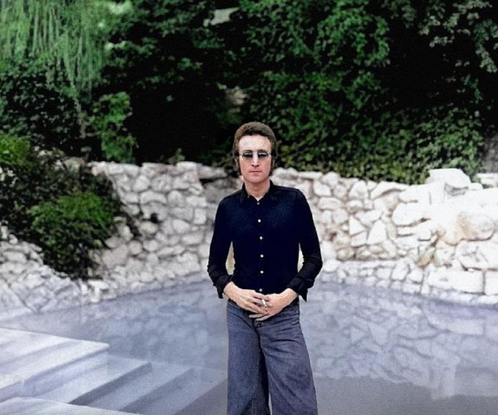 John Lennon w czarnej koszuli i okularach na tle basenu. O jego ulubionym albumie The Beatles przeczytasz na EskaRock.