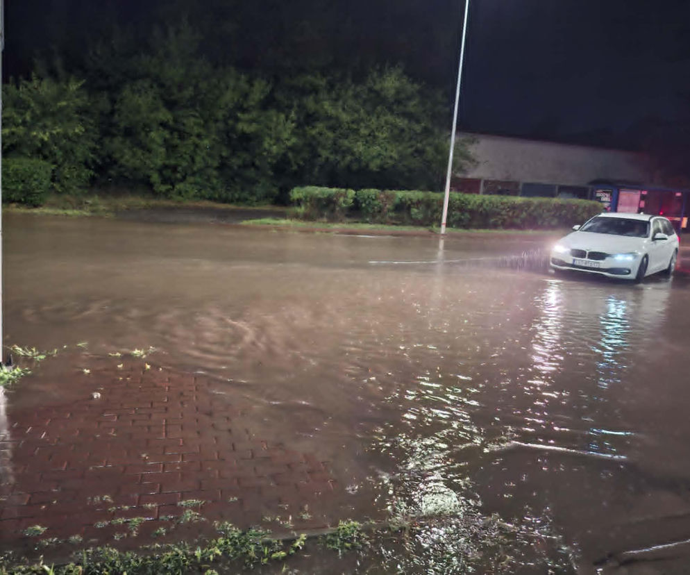 Biały samochód przejeżdżający nocą przez zalane skrzyżowanie. O skutkach burzy przeczytasz na Eska Starachowice.