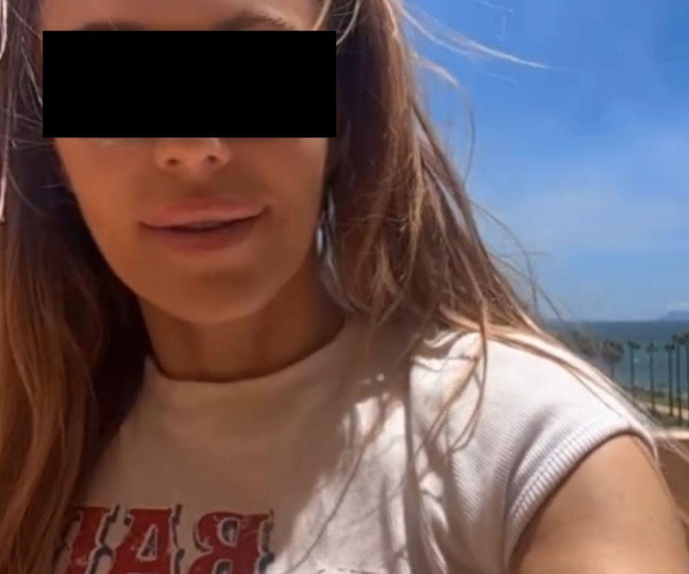 Dorota R. w ujęciu z bliska, z zasłoniętymi oczami, z uśmiechem na twarzy, na wakacjach, z widokiem na morze i palmy w tle. Piosenkarka komentuje swoje zarzuty prokuratorskie. Więcej o tej sprawie przeczytasz na naszym portalu.