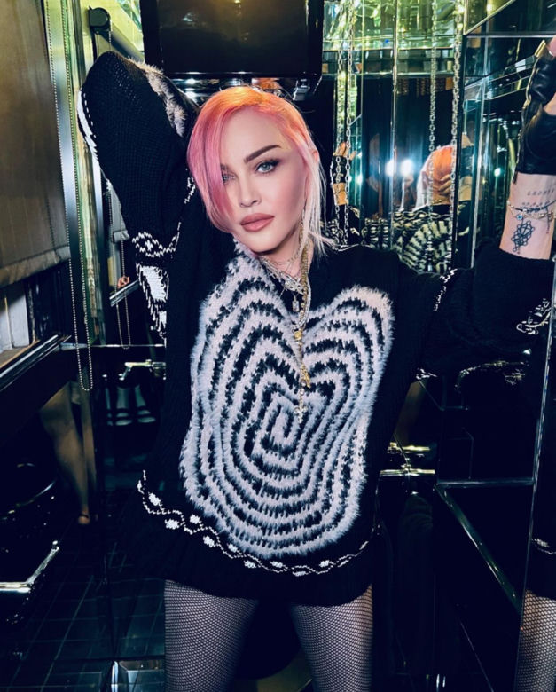 Madonna w kominiarce rzuca się w konwulsjach po łóżku. W ręce trzyma pejcz. "Ocknij się kobieto"