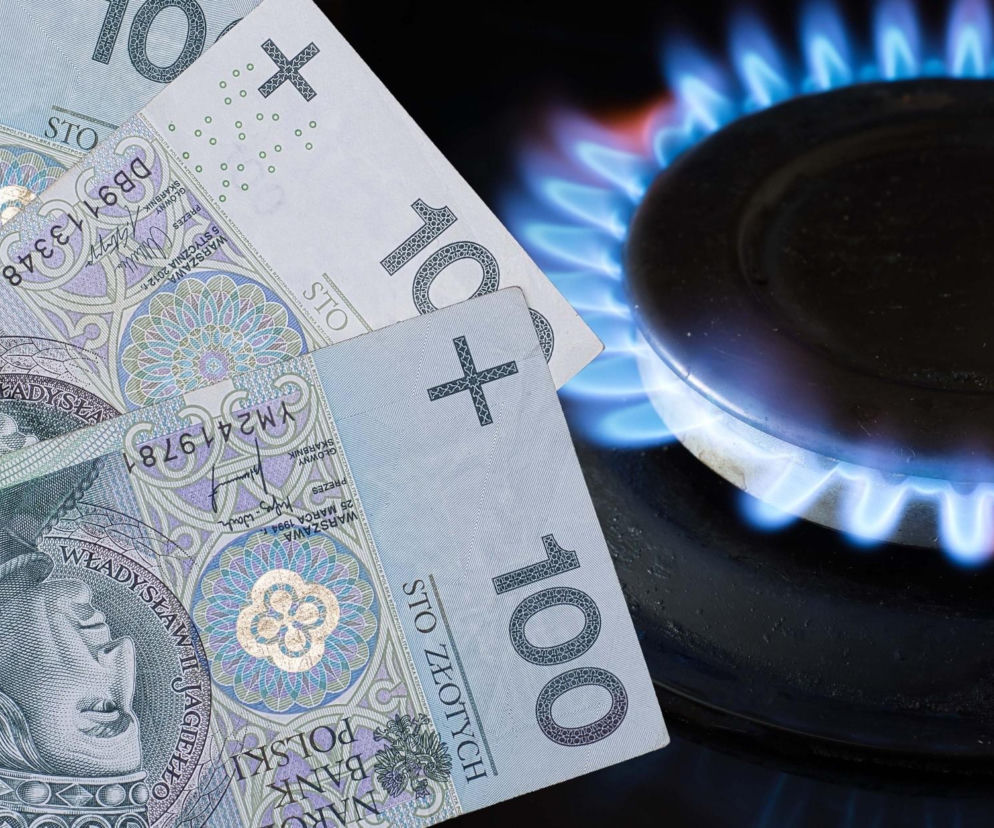 Banknoty 100 złotowe leżące obok palnika kuchenki gazowej z widocznym błękitnym płomieniem. Symbolika obrazuje rosnące koszty gazu w Polsce, o których można przeczytać na Super Biznes.