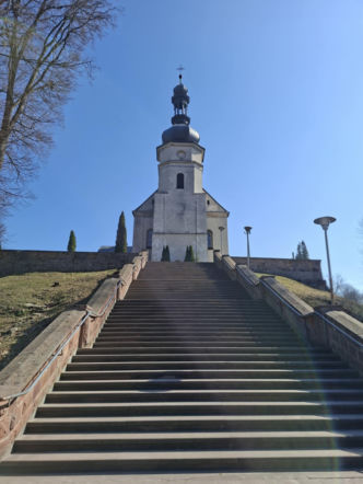 Widok z dołu na monumentalne schody z czerwonego piaskowca, pnące się ku wzgórzu kościelnemu.