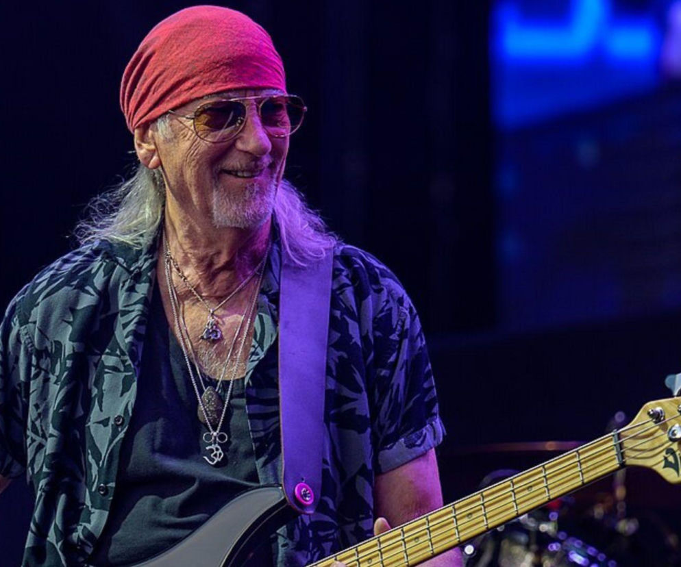 Uśmiechnięty Roger Glover z Deep Purple gra na gitarze basowej. O historii Smoke on the Water przeczytasz na EskaRock.