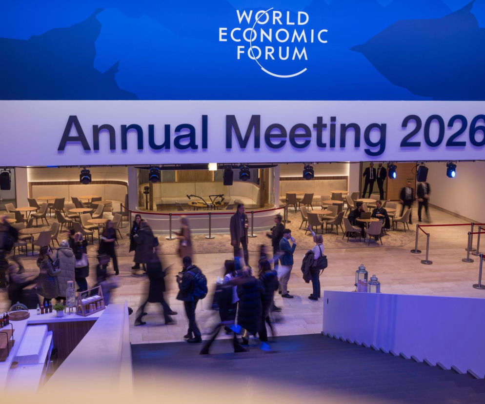 Wnętrze centrum konferencyjnego podczas Światowego Forum Ekonomicznego w Davos z logo World Economic Forum i napisem Annual Meeting 2026. Liczni uczestnicy, w tym biznesmeni i politycy, przemieszczają się między strefami spotkań, omawiając globalne wyzwania, o czym można przeczytać na Super Biznes.