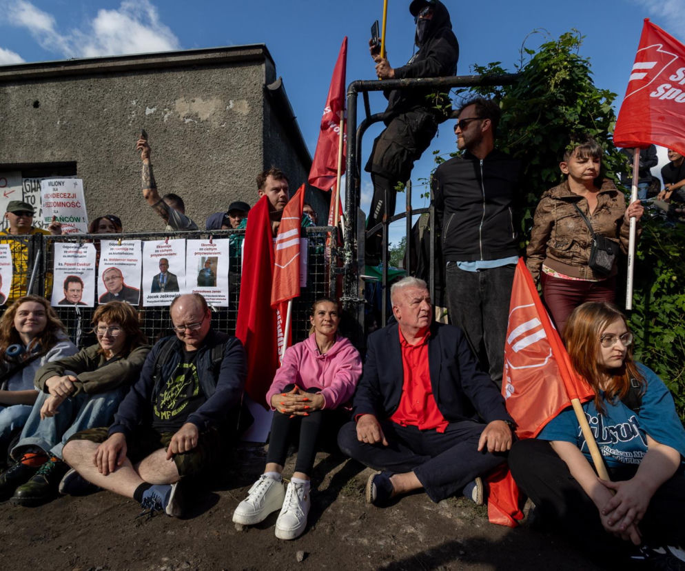 Piotr Ikonowicz i aktywiści siedzą pod bramą posesji. O proteście przeciw eksmisji w Poznaniu przeczytasz na Eska Poznań.