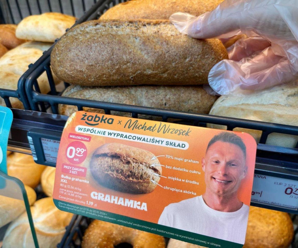 Osoba w rękawiczce wybiera bułkę grahamkę w sklepie Żabka. O nowościach w menu sieci przeczytasz na portalu Eska.