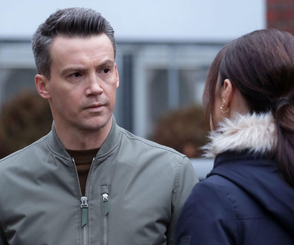 Jakub (Krzysztof Kwiatkowski) w oliwkowej kurtce rozmawia z Martyną (Magdalena Turczeniewicz) odwróconą tyłem, w granatowej kurtce z futrem. Scena przedstawia ostrą kłótnię bohaterów w 1924 odcinku M jak miłość. Więcej o serialu znajdziesz na Super Seriale.