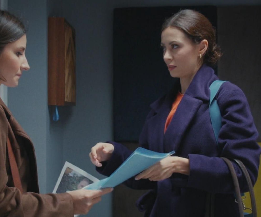 Agnes (Amanda Mincewicz) w brązowej kurtce i Joanna (Dominika Sakowicz) w fioletowym płaszczu wymieniają dokumenty w gabinecie. Joanna trzyma niebieską teczkę, a Agnes patrzy na zdjęcie, które ma w ręku. To kluczowa scena w wątku szpiegowania Artura Rogowskiego, który możesz śledzić na stronie Super Seriale.
