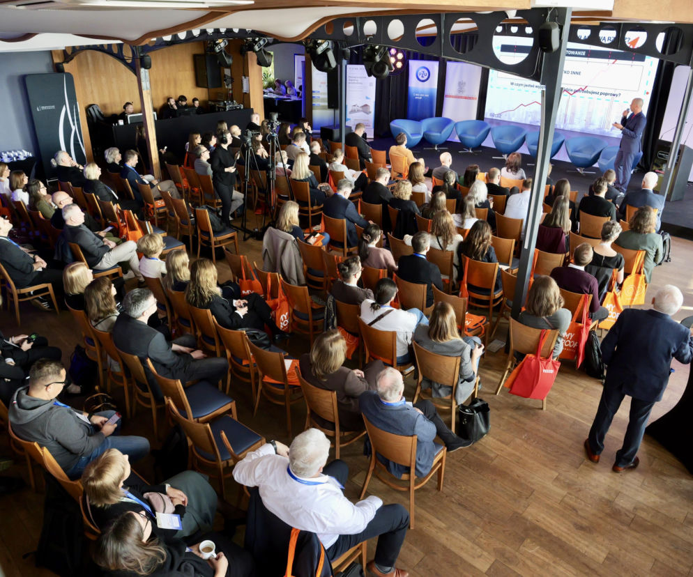 Uczestnicy konferencji IARP siedzą w sali z widokiem na prelegenta przy ekranie. O biznesie architekta czytaj w Architektura.