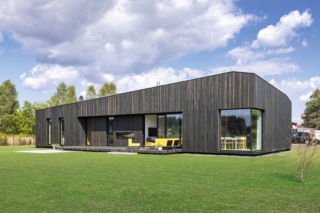 Dom parterowy z elewacją z opalanego, czarnego drewna. Dach też jest czarny