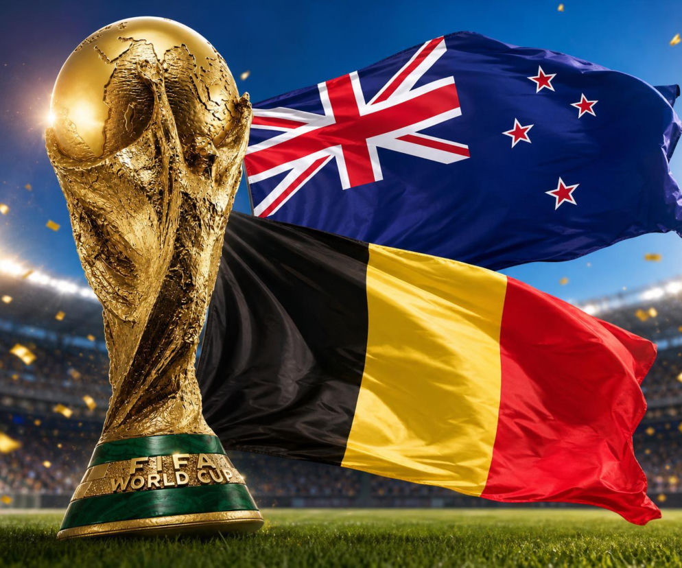 Puchar Świata FIFA, symbol mundialu, stojący na trawie stadionu piłkarskiego, z powiewającymi w tle flagami Nowej Zelandii i Belgii. W tle widać publiczność na trybunach. Więcej o statystykach meczu przeczytasz na naszym portalu.