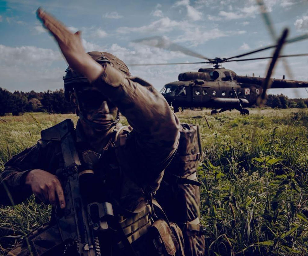 Żołnierz w pełnym ekwipunku na polu, za nim widać helikopter. O rozwoju armii przeczytasz na SE Portal Obronny.