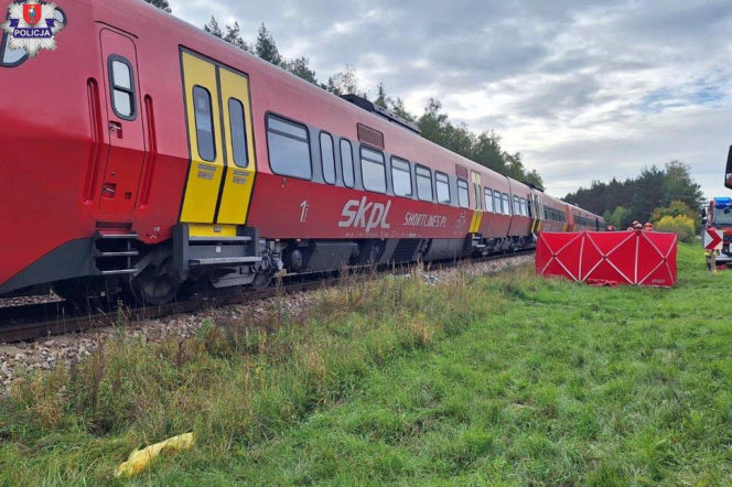 Czerwony pociąg pasażerski stoi na torach. Obok czerwony parawan ratowniczy. O wypadku w Bagnie czytaj w Eska Lublin.