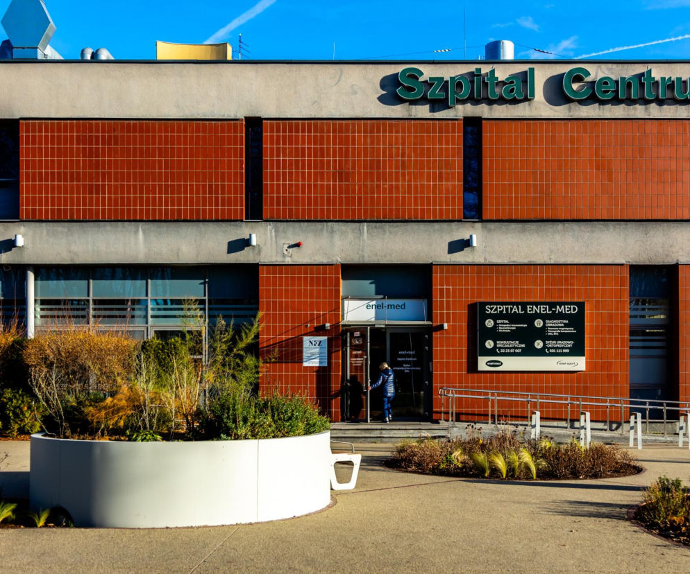 Fasada budynku Szpitala Centrum Enel-Med z ceglanymi panelami i przeszkleniami, otoczona suchymi krzewami i roślinnością, oddająca obecny wygląd dawnego pawilonu Wenecja na Woli. O zmianach i historii tego miejsca przeczytasz na portalu Architektura Murator Plus.