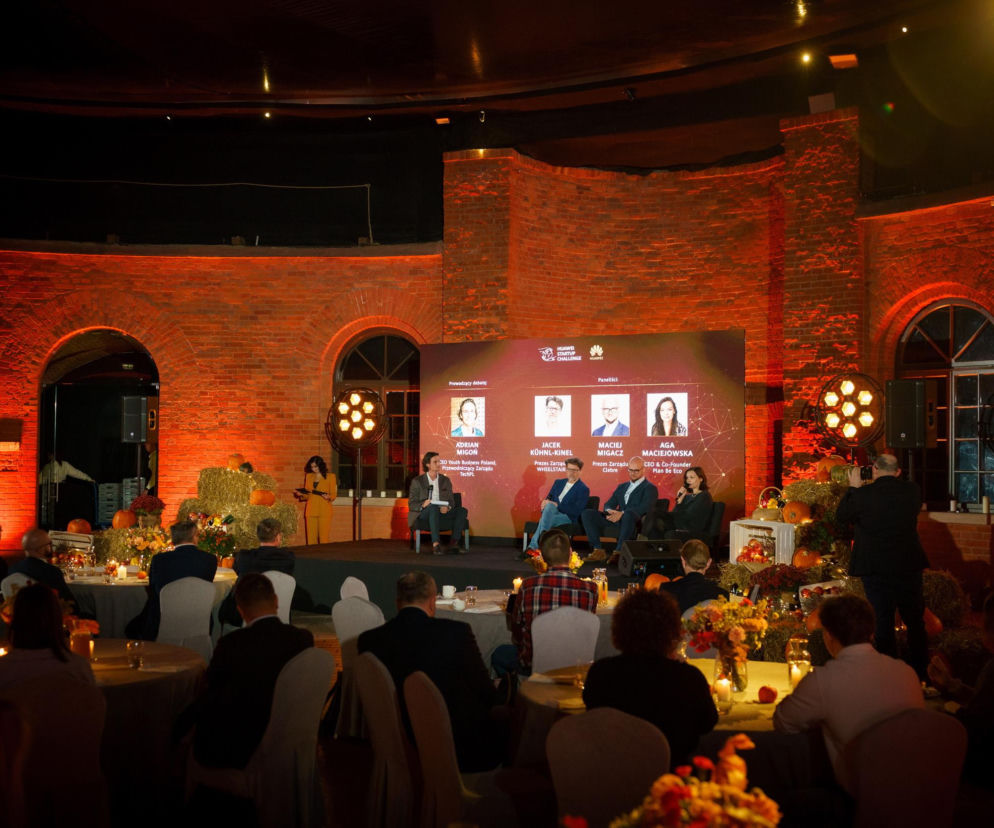 Panel dyskusyjny podczas konferencji Huawei Startup Challenge z udziałem Adriana Migonia, Jacka Kühnl-Kinela, Macieja Migacza i Agi Maciejowskiej. Sala udekorowana w jesiennym stylu, z publicznością siedzącą przy stołach, co można przeczytać na Super Biznes.