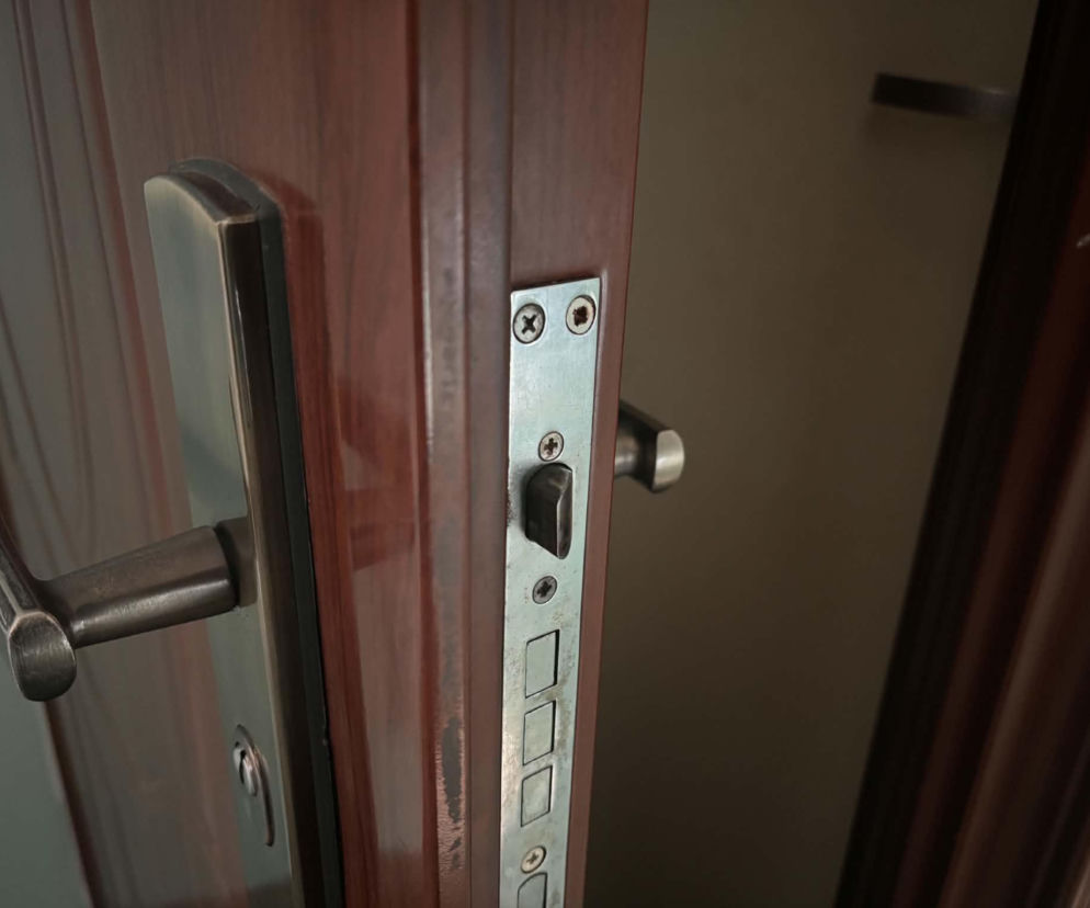 Zbliżenie na klamkę i mechanizm zamka w otwartych drzwiach drewnianych. O uszczelnianiu drzwi przeczytasz na Muratordom.