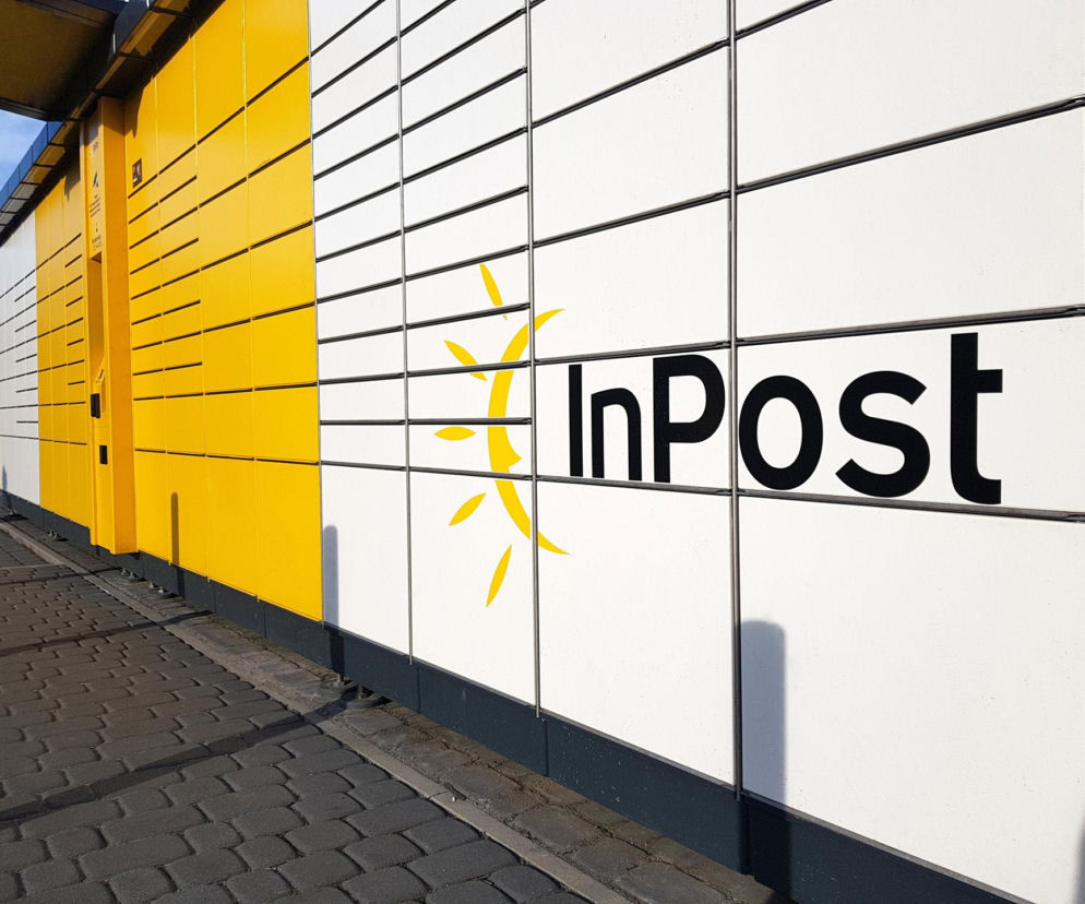 Biało-żółty Paczkomat z dużym logo InPost na chodniku. O fuzji za miliardy złotych przeczytasz na SE Superbiz.