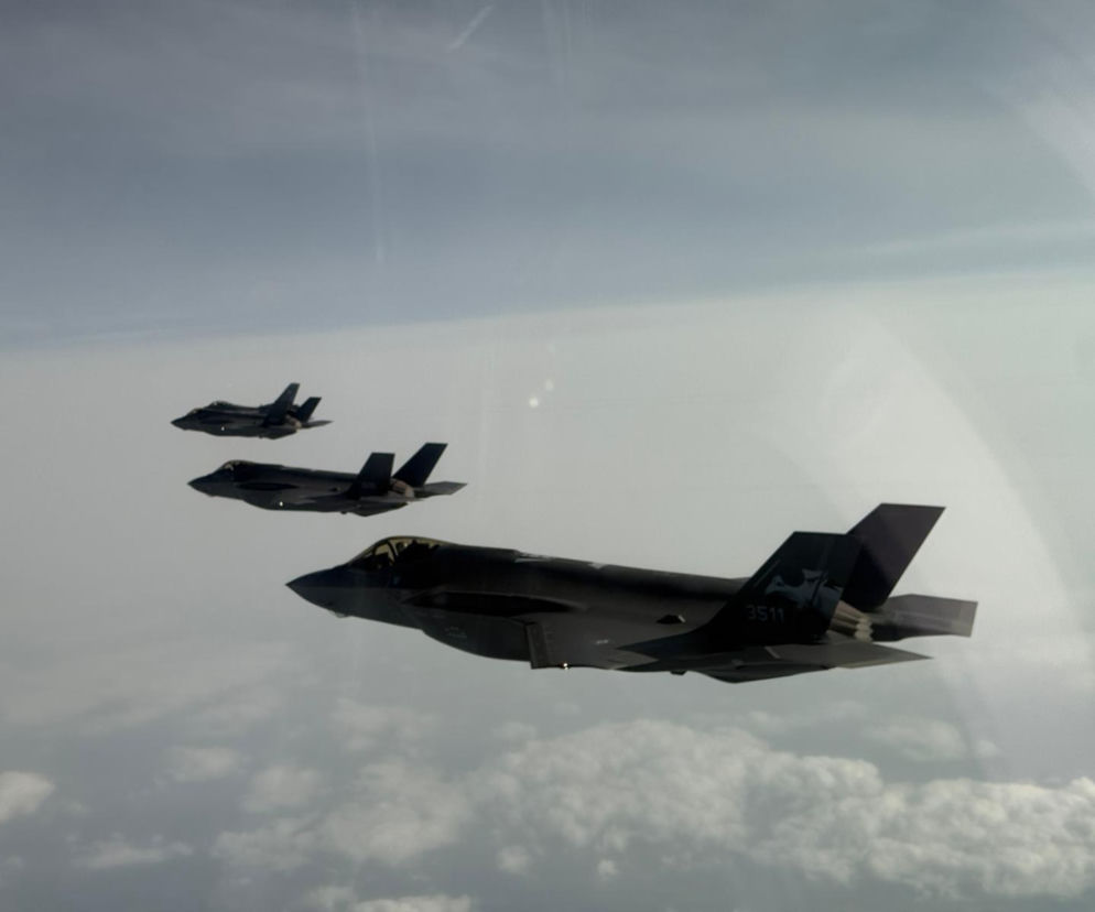 Trzy myśliwce F-35 Husarz lecą w formacji na tle zachmurzonego nieba, z widocznym numerem 3511 na ogonie jednej z maszyn. Informacje o rajdzie F-35 nad Polską i znaczeniu tych samolotów dla obronności można przeczytać na Super Biznes.