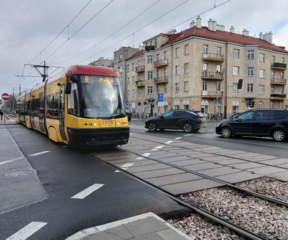 Ulica Grójecka w Warszawie, z widocznym żółto-czerwonym tramwajem linii 9 i jadącymi samochodami. Po prawej stronie kamienice z czerwonymi dachami, a na pierwszym planie torowisko tramwajowe. O problemach komunikacyjnych w tej części Ochoty przeczytasz na portalu Architektura Murator Plus.