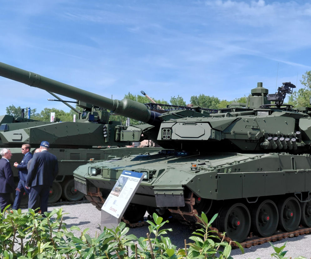 Czołg Leopard 2 na wystawie zbrojeniowej. Obok stoją trzej mężczyźni. O przyszłości KNDS przeczytasz na SE Portal Obronny.