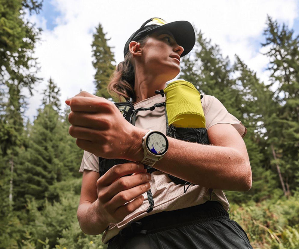 Kobieta w stroju sportowym zerka na zegarek Suunto Race 3S z mapą na ekranie. O premierze modelu przeczytasz na Eska.
