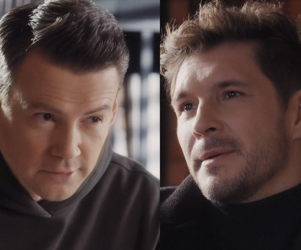 Zbliżenie na dwóch mężczyzn: po lewej Krzysztof Kwiatkowski jako Jakub Karski w ciemnej bluzie z kapturem, po prawej Mikołaj Roznerski jako Marcin Chodakowski z zarostem i w czarnym golfie. Obaj spoglądają z zamyśloną miną, co wskazuje na intrygę i kłamstwa kryjące się w fabule M jak miłość, o czym przeczytasz więcej na Super Seriale.