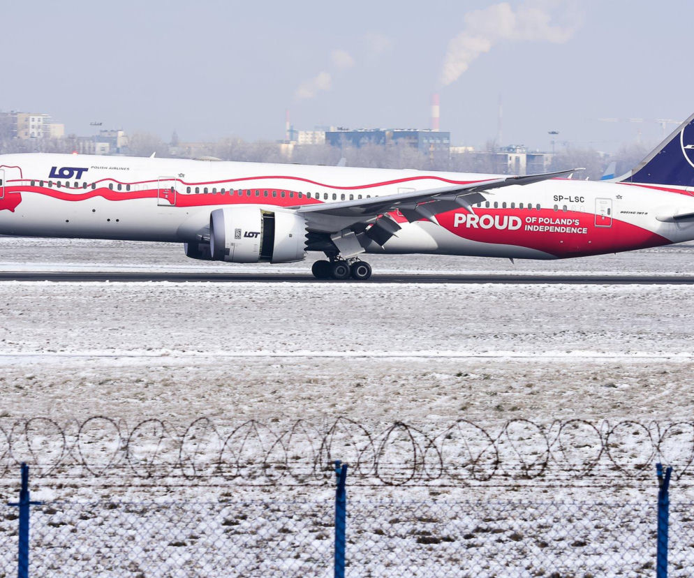 Samolot Boeing 787 Dreamliner Polskich Linii Lotniczych LOT, z malowaniem „Proud of Poland’s Independence”, stoi na zaśnieżonym pasie startowym Lotniska Chopina w Warszawie. Zdjęcie ilustruje problemy z opóźnieniami lotów zimą, o czym przeczytasz na Super Biznes.