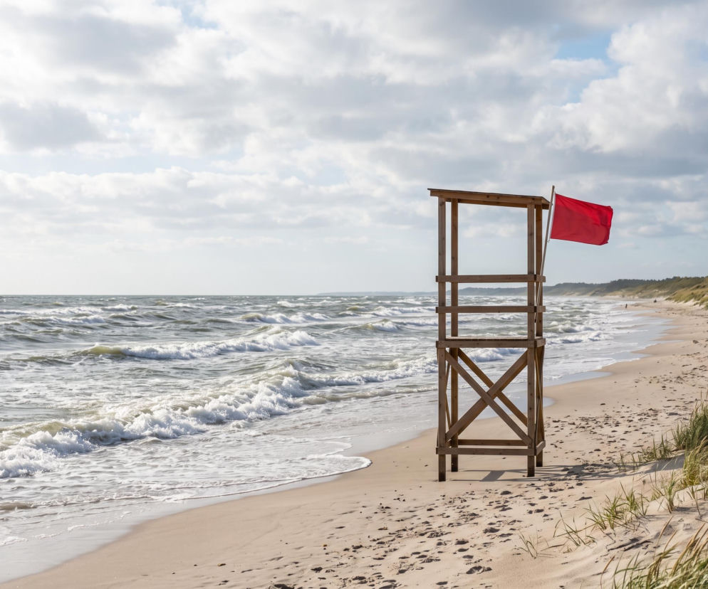 Czerwona flaga na wieży ratowniczej przy pustej plaży w Darłowie. O zakazie kąpieli przeczytasz na SE Szczecin.
