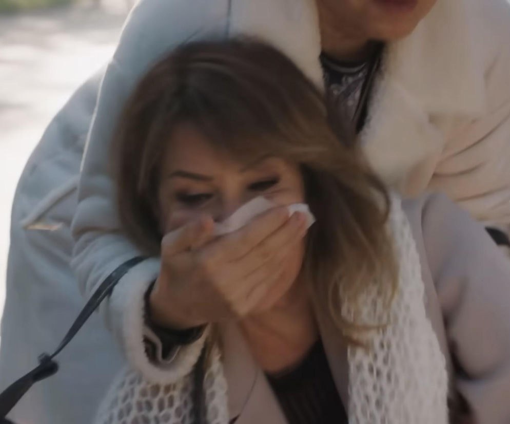 Kobieta o blond włosach w jasnym płaszczu z szalikiem na szyi zostaje porwana, z ustami zakrytymi przez inną osobę, której widać rękę w tle. Dramatyczny moment uprowadzenia Feraye z serialu Miłość i Nadzieja, o którym przeczytasz więcej na Super Seriale.