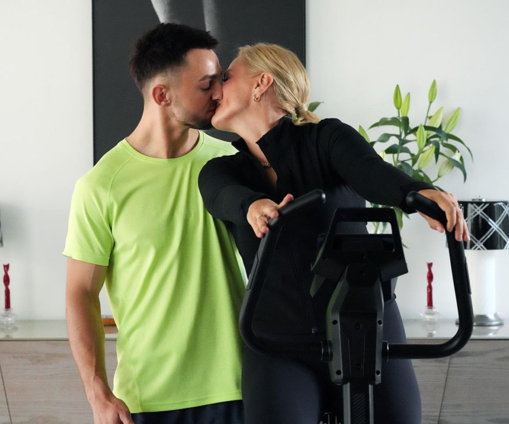 Mirek (Oliwier Kozłowski) i Justyna (Sylwia Juszczak-Krawczyk) z Barw szczęścia całują się na tle domowego sprzętu do ćwiczeń. Scena ilustruje namiętny związek bohaterów serialu, o którym przeczytasz więcej na portalu Super Seriale.