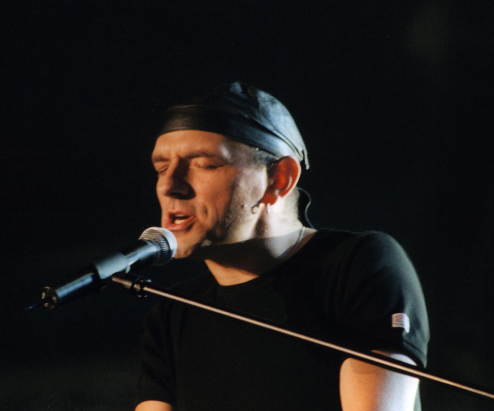 Grzegorz Stróżniak z zespołu Lombard śpiewa do mikrofonu. O historii utworu Przeżyj to sam przeczytasz na Eska2.