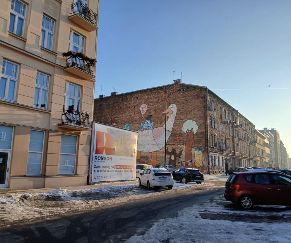 Działka między kamienicami przy ulicy Brzeskiej z reklamą dewelopera i muralem. O inwestycji przeczytasz na Muratorplus.
