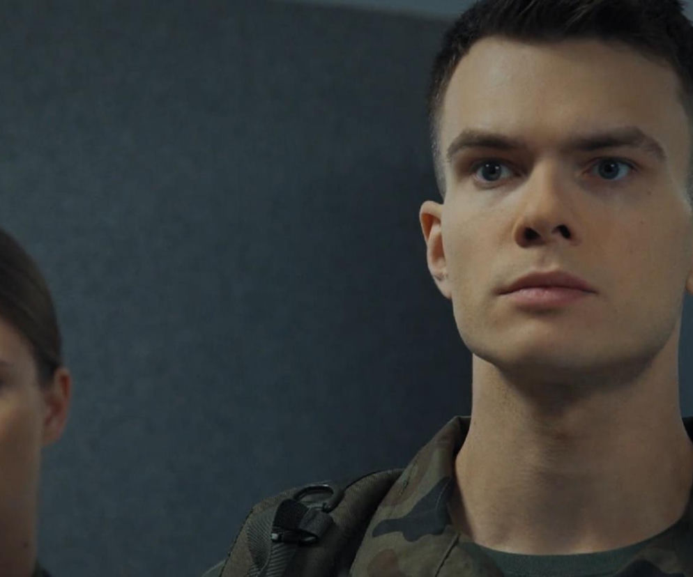 Tomek (Chris Cugowski) i Majka (Matylda Giegżno) w mundurach, zamyśleni. Majka patrzy w dal, a Tomek ma poważny wyraz twarzy. Scena oddaje napięcie w związku postaci z M jak miłość. Więcej informacji o serialowych perypetiach bohaterów znajdziesz na portalu Super Seriale.