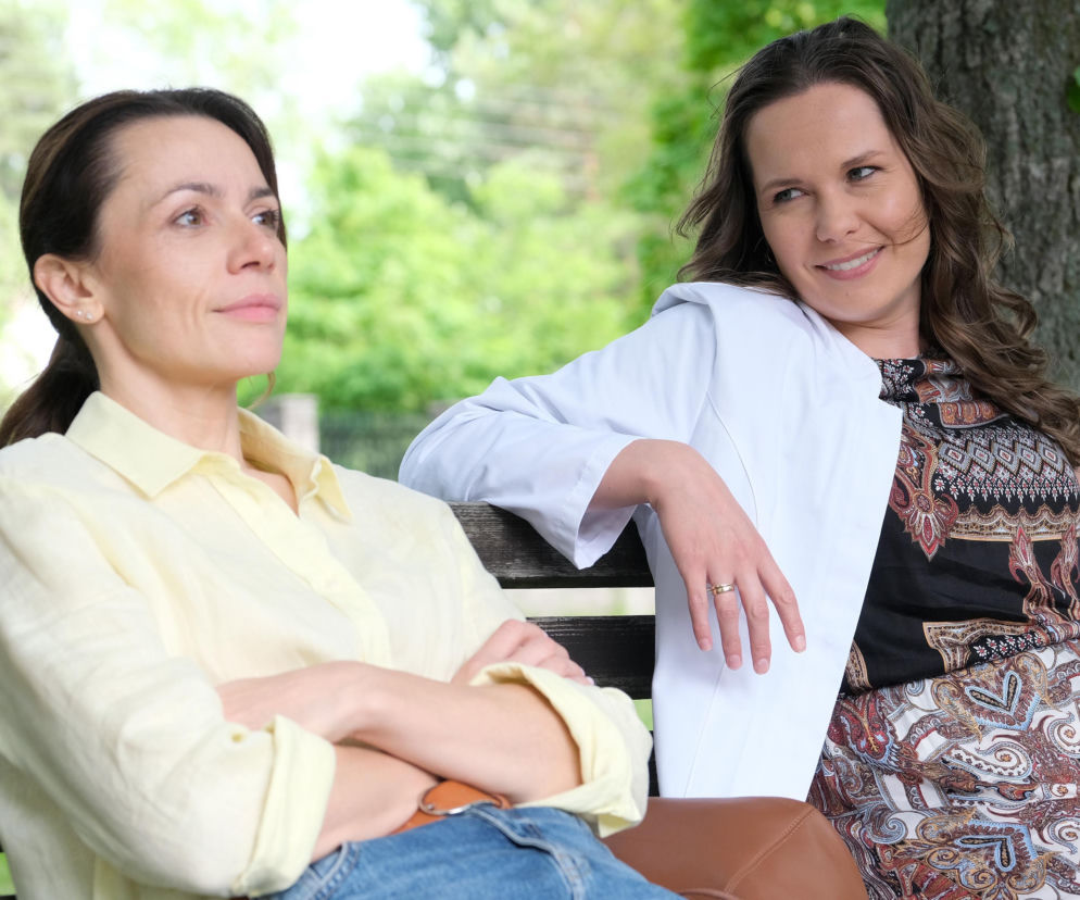 Martyna (Magdalena Turczeniewicz) i Agata (Lidia Pronobis) siedzą na ławce w parku. Martyna ma skrzyżowane ręce i patrzy w dal, natomiast Agata uśmiecha się, opierając się o ławkę. Kobiety rozmawiają o relacji Martyny z Marcinem, co można przeczytać na Super Seriale.