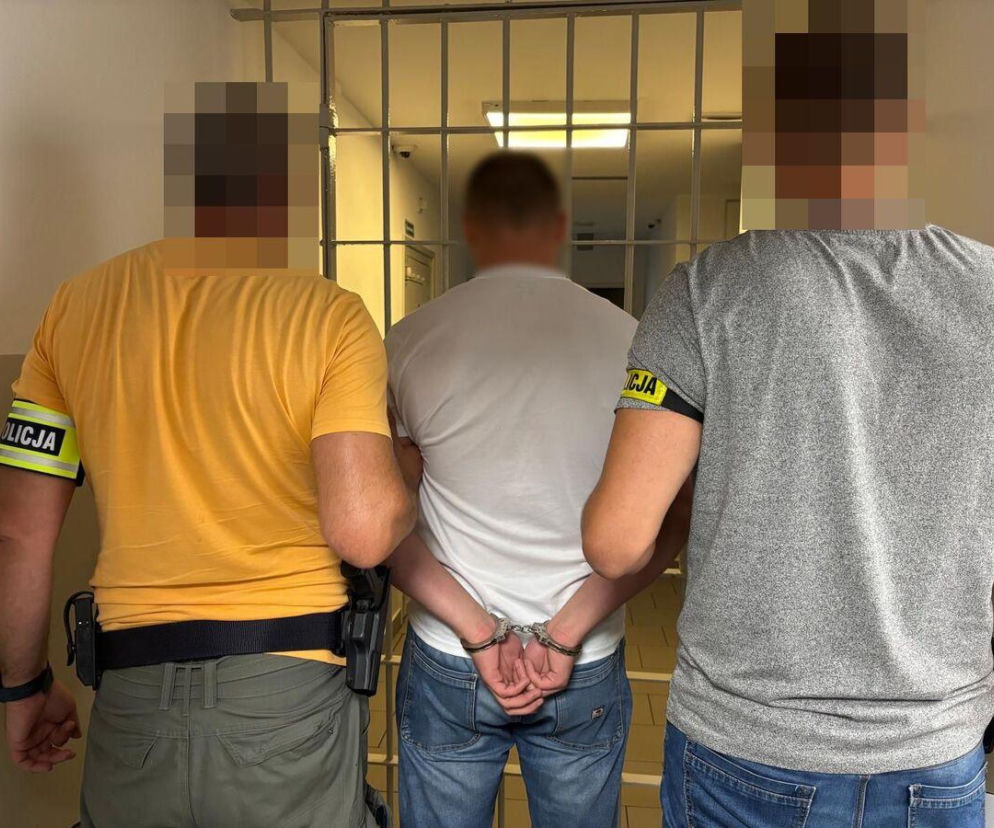 Dwaj policjanci prowadzą skutego kajdankami mężczyznę do celi. O wypadku w Siekierzyńcach przeczytasz na Eska Lublin.