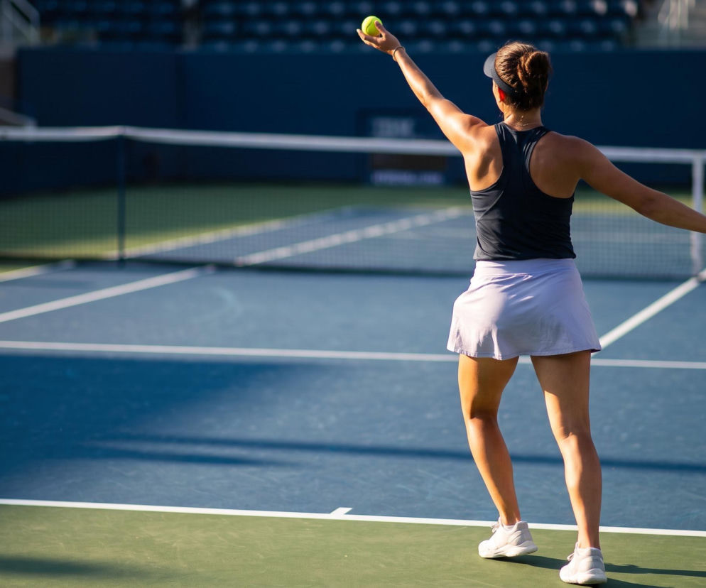 Tenisistka przygotowuje się do serwisu na korcie. O zmianach w rankingu WTA i pozycji Igi Świątek przeczytasz na Eska.