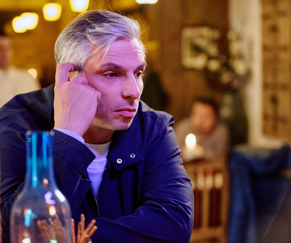 Zamyślony Krzysztof Smolny w lokalu. O losach bohaterów serialu Na Wspólnej przeczytasz na VOX FM.