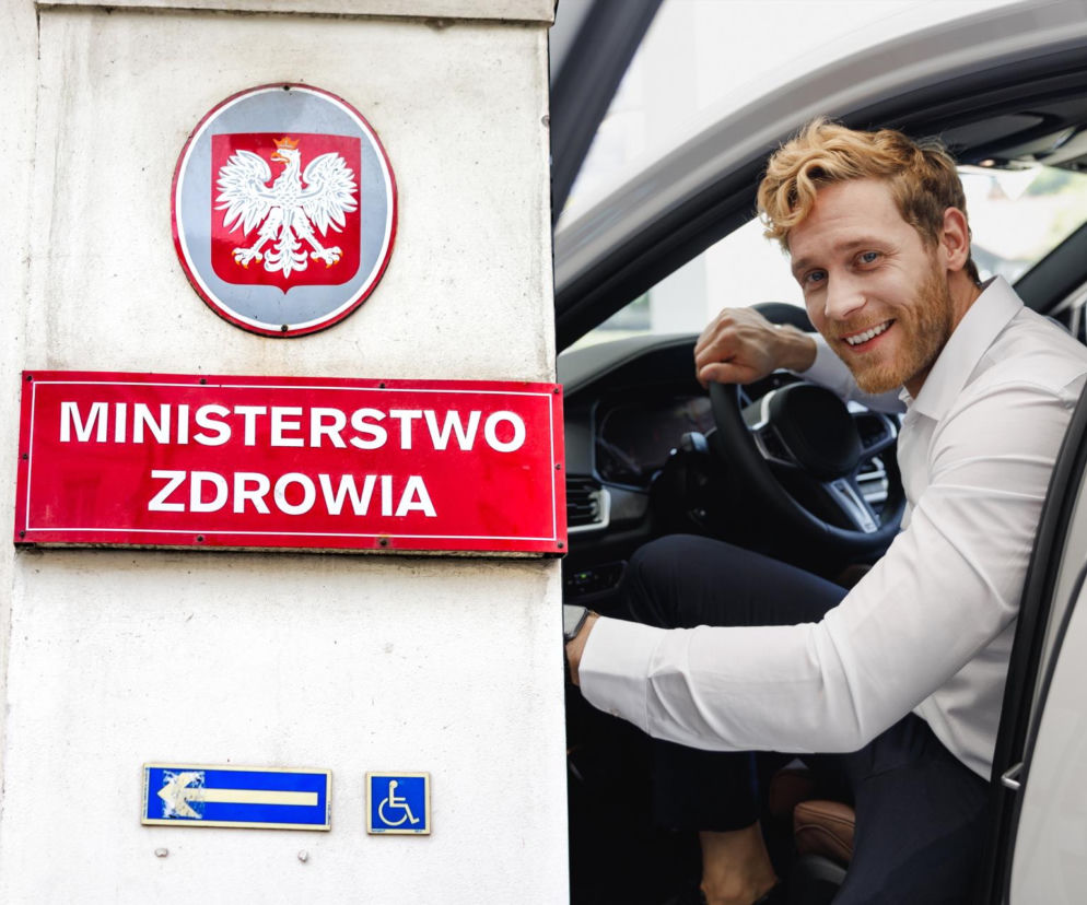 Mężczyzna uśmiechnięty w samochodzie, obok tablica z napisem Ministerstwo Zdrowia. Zdjęcie ilustruje temat podwyżek za obowiązkowe badania dla kierowców, o czym można przeczytać na Super Biznes.