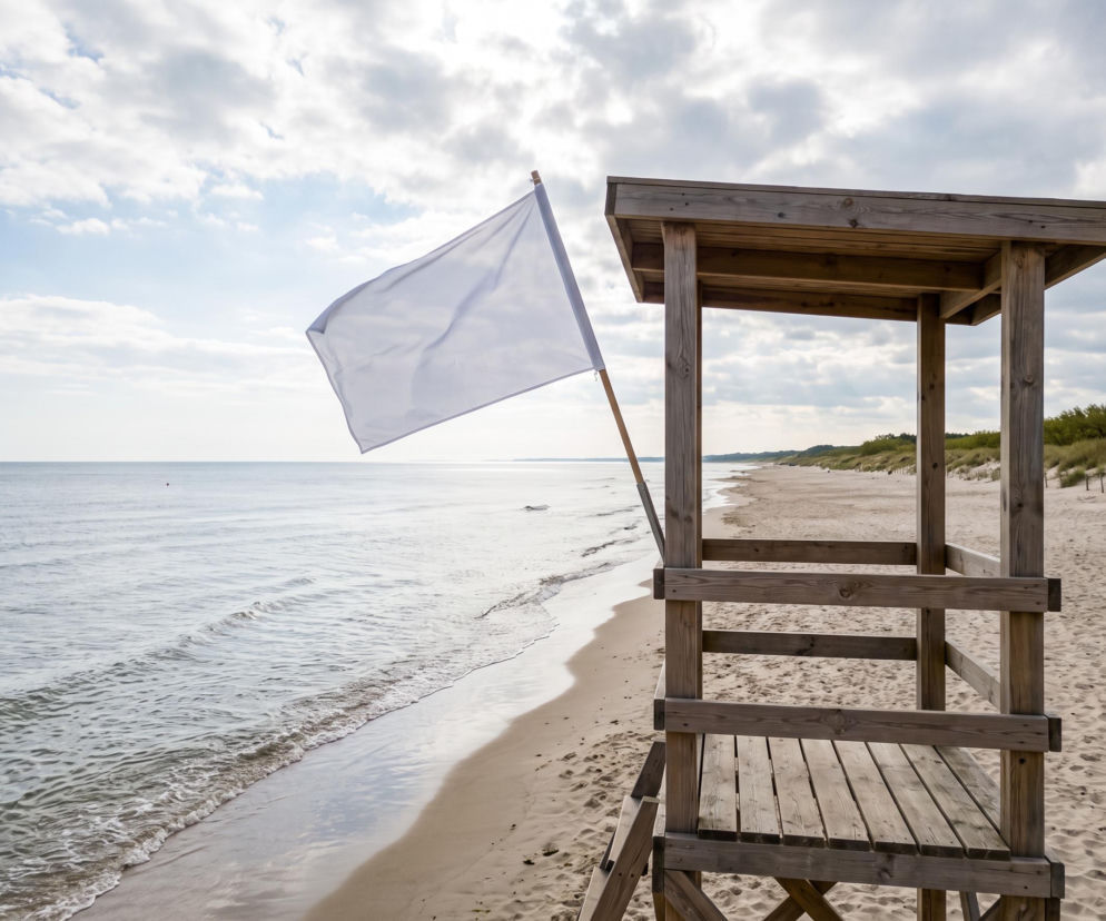 Biała flaga na wieży ratowniczej przy pustej plaży w Chałupach. O warunkach kąpieli przeczytasz na Eska Trójmiasto.