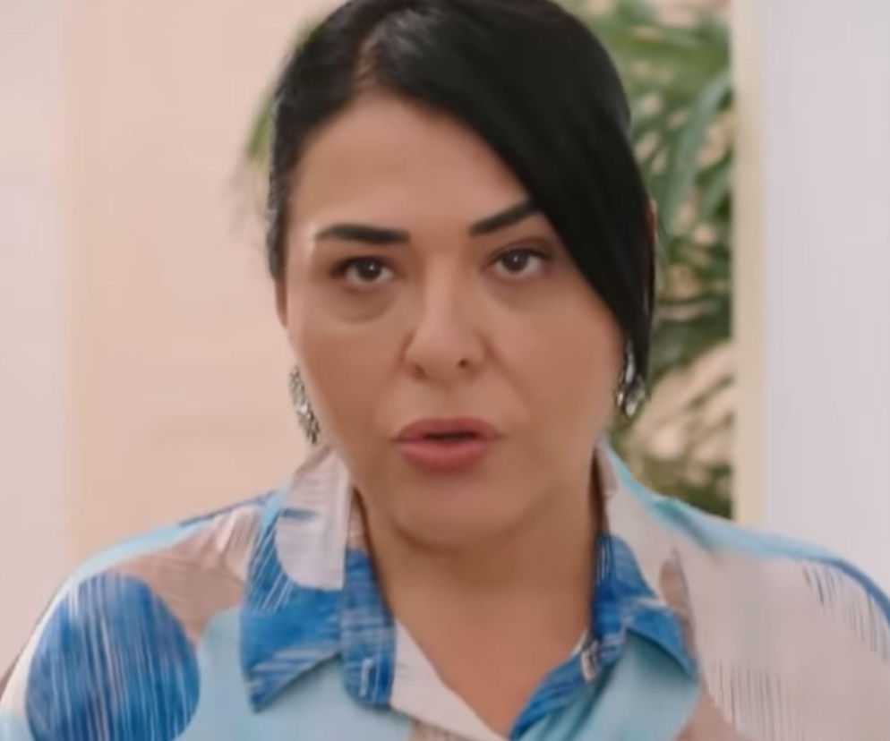 Aktorka Betigül Ceylan jako Mukadder Develioglu w zbliżeniu na twarz, w koszuli w biało-niebieskie wzory, z ciemnymi włosami zaczesanymi do tyłu, z ustami otwartymi, wyrażająca emocje. Więcej o tureckiej telenoweli Panna młoda przeczytasz na stronie Super Seriale.