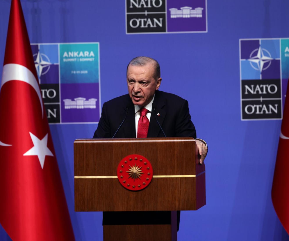 Prezydent Turcji Recep Tayyip Erdogan przemawia na tle flag i logo NATO. O nietypowych prezentach przeczytasz w Eska.