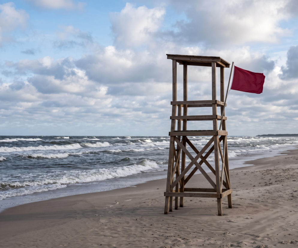 Czerwona flaga przy pustej wieży ratowniczej na plaży w Międzyzdrojach. O zakazie kąpieli przeczytasz na SE Szczecin.