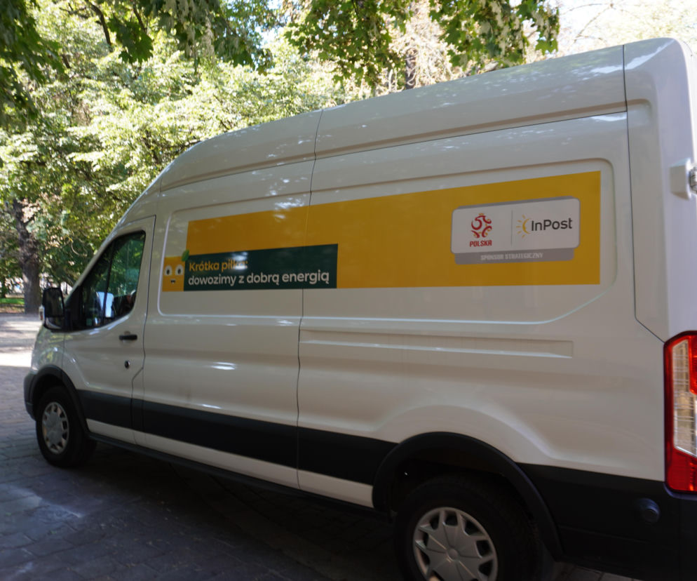 Biały samochód dostawczy InPost z napisem Krótka piłka: dowozimy z dobrą energią, zaparkowany na ulicy Wiślnej, w tle drzewa. Informacje o zakończeniu konfliktu Allegro z InPostem przeczytasz na portalu Super Biznes.