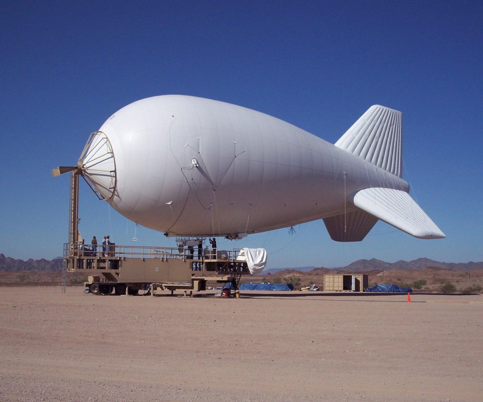 Biały aerostat rozpoznawczy na uwięzi na tle nieba i gór. O programie Barbara przeczytasz na SE Portal Obronny.