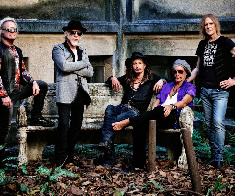 Muzycy Aerosmith pozują przy kamiennej ławce. O powrocie legend rocka na koncerty przeczytasz na EskaRock.