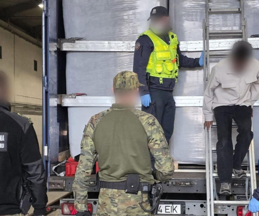 Funkcjonariusze przy ciężarówce, z której po drabinie schodzi migrant. O akcji w Budzisku czytaj na Eska Białystok.