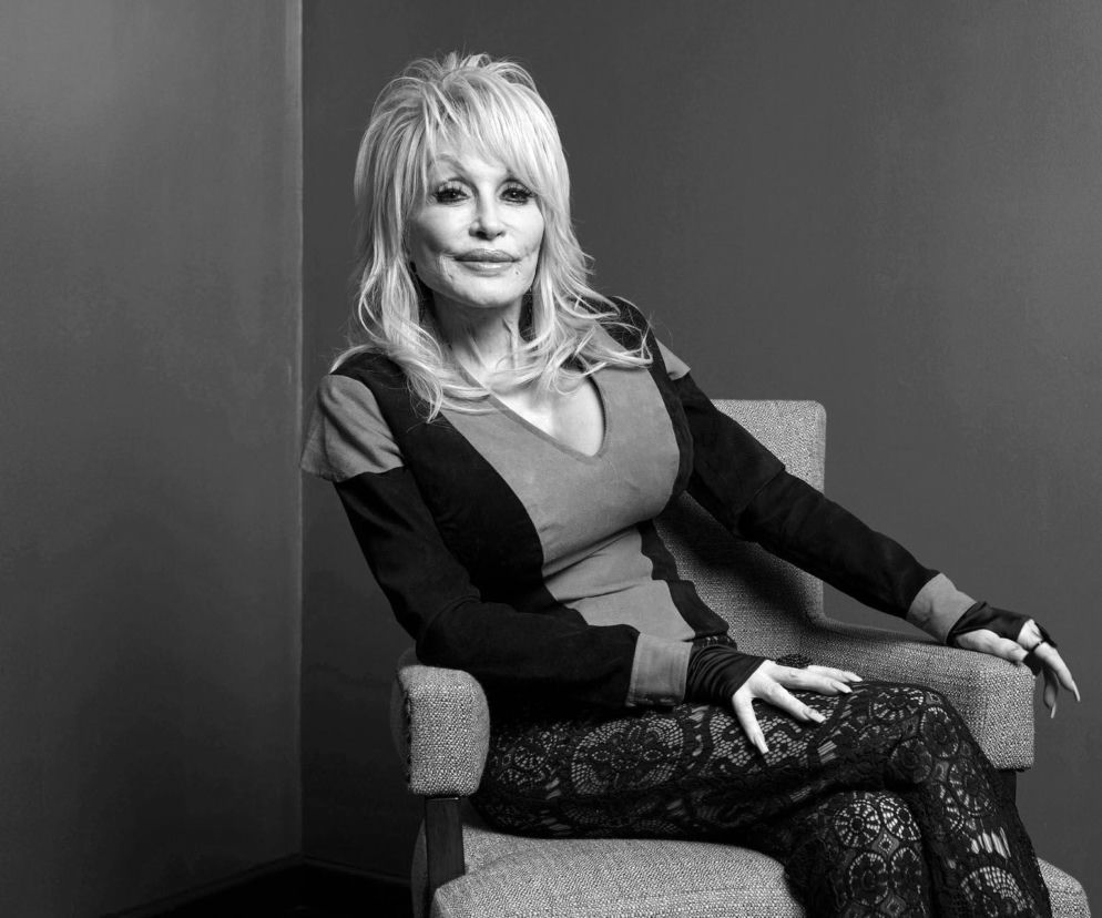 Dolly Parton siedzi na fotelu w ciemnej sukience. O śmierci legendarnej gwiazdy country przeczytasz na SE.