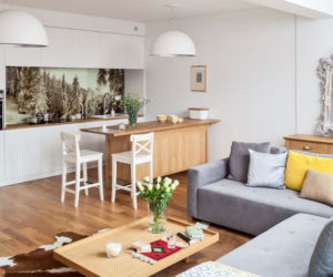 Szara, narożna sofa w salonie łączonym z kuchnią