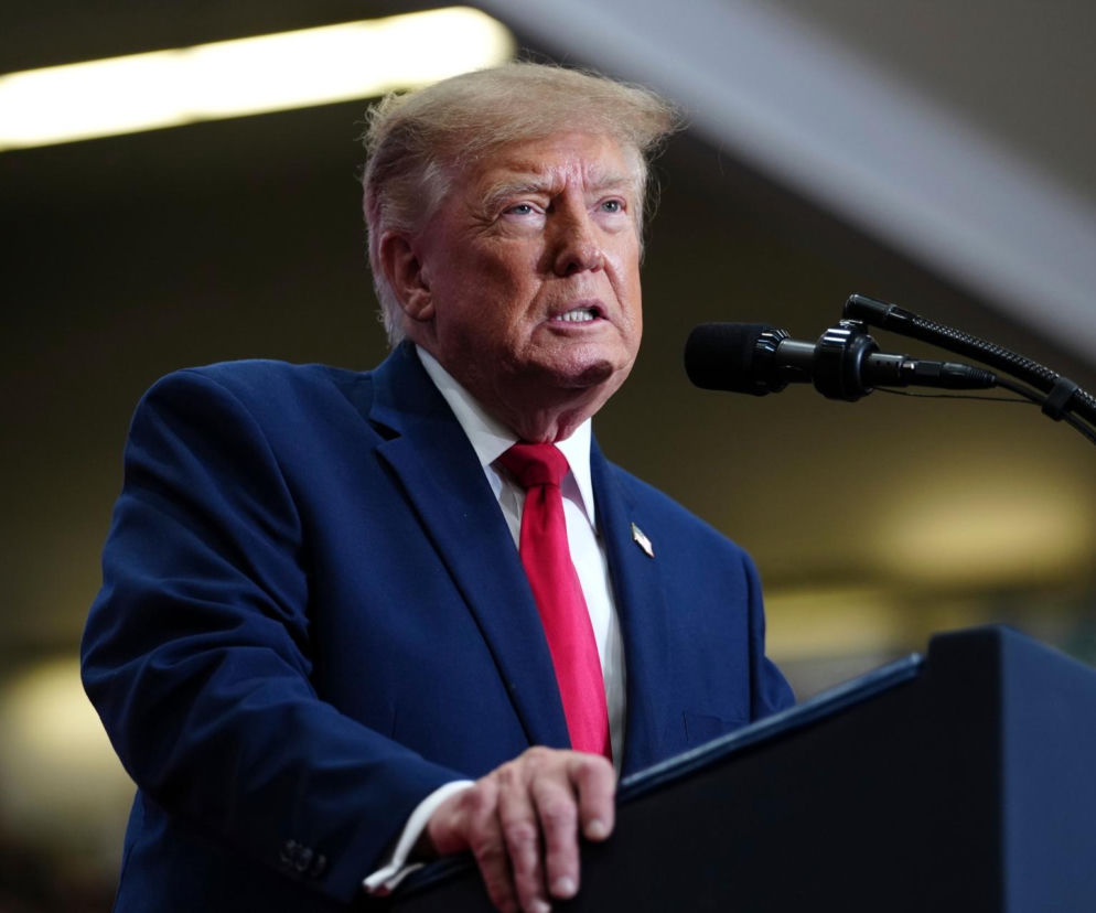 Donald Trump przemawia przy mównicy. O kontrowersjach wokół zysków USA z wojny z Iranem przeczytasz na SE Superbiz.