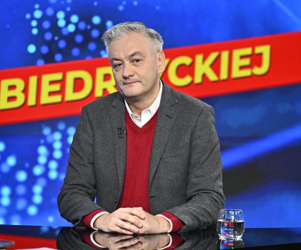 Robert Biedroń w studiu, siedzi przy stole ze złożonymi dłońmi. O politykach prawicy przeczytasz na SE Polityka.